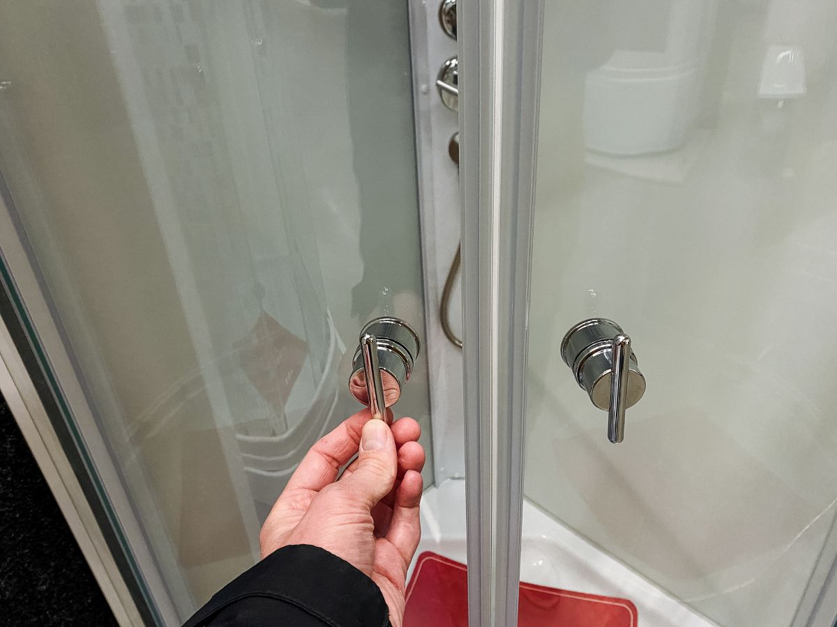 technician adjusting shower handle during routine plumbing inspection and testing