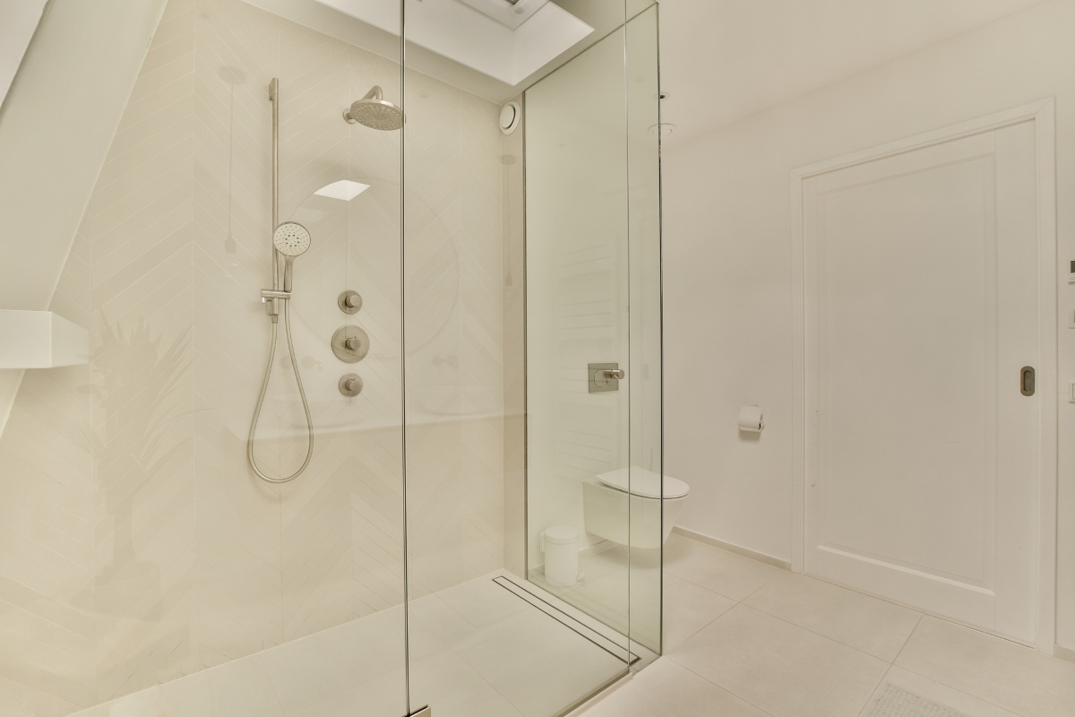 A bathroom with a glass shower door and a toilet